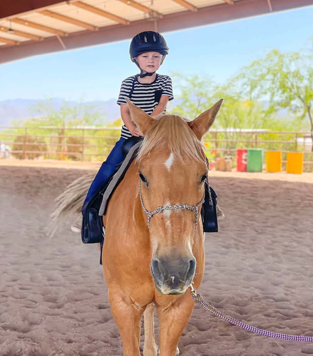 young child in arena during riding lesson